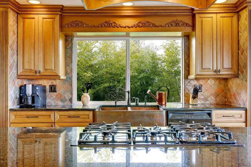 Narrow beige and yellow kitchen with cabinets and big window