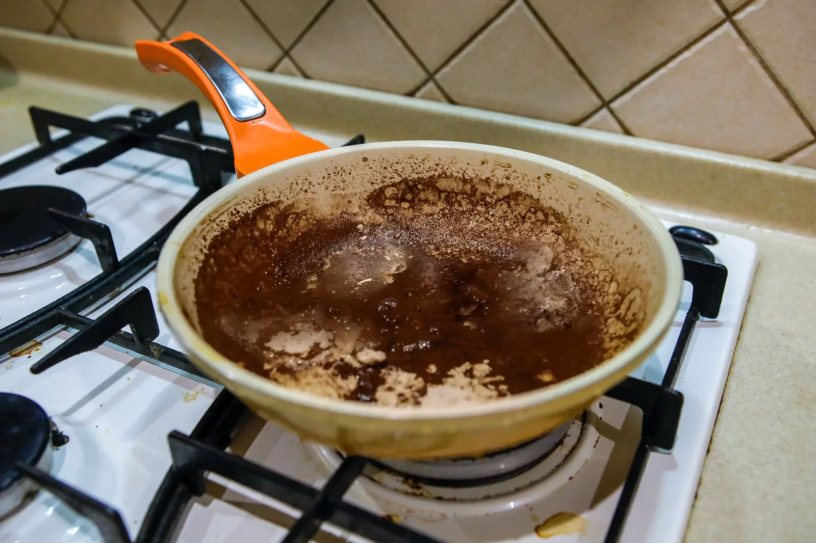 On the stove is a dirty, burnt, unwashed pan, close-up